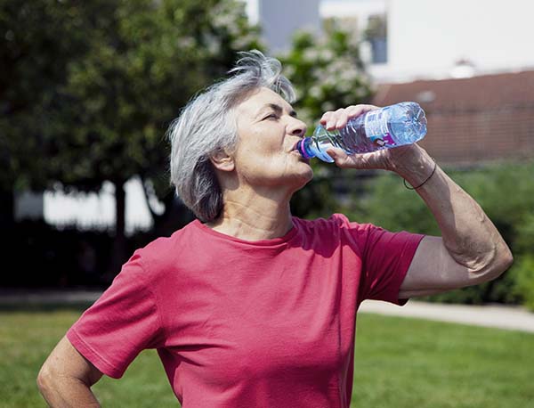 Ältere Frau trinkt aus einer Wasserflasche